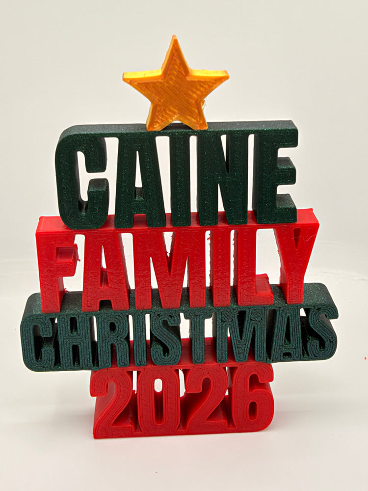 Caine Family Christmas 2026 tree-shaped ornament with dark green and red lettering and a gold-colored star.